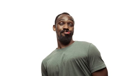 Beyaz stüdyo arka planında izole edilmiş komik, alışılmadık popüler duyguları ve jestleri olan genç Afro-Amerikan bir adam.