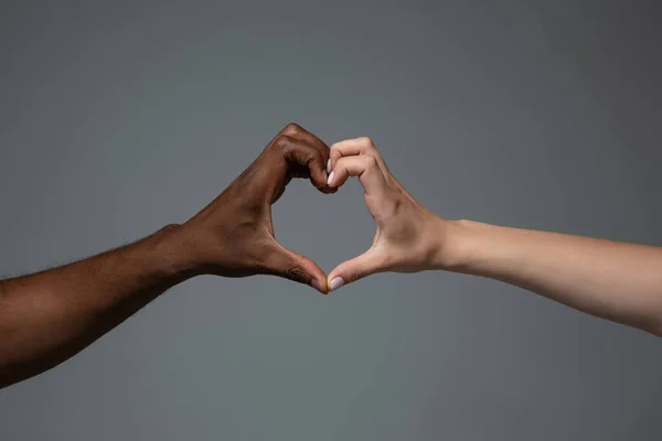 Rasetoleranse. Respekter sosial enhet. Afrikanske og kaukasiske hender som gestikulerer isolert på bakgrunn av grått studio – stockfoto