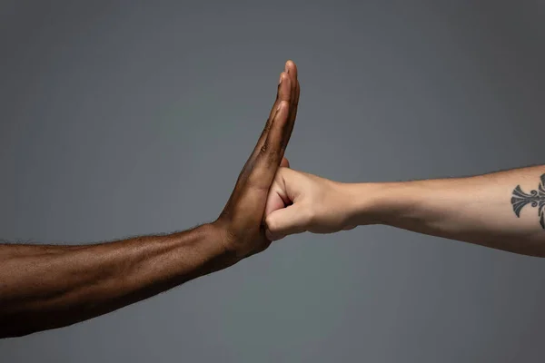 Tolerancia racial. Respetar la unidad social. Africano y caucásico manos gesto aislado en gris estudio fondo — Foto de Stock