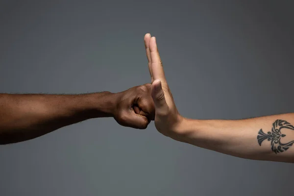 Raciale tolerantie. Respecteer de sociale eenheid. Afrikaanse en Kaukasische handen gebaren geïsoleerd op grijze studio achtergrond — Stockfoto