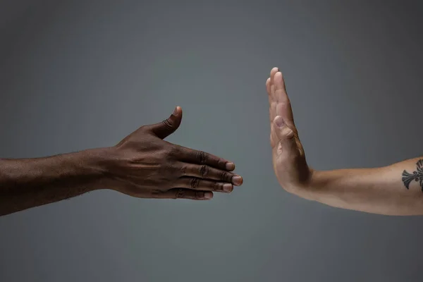 Tolerancia racial. Respetar la unidad social. Africano y caucásico manos gesto aislado en gris estudio fondo — Foto de Stock