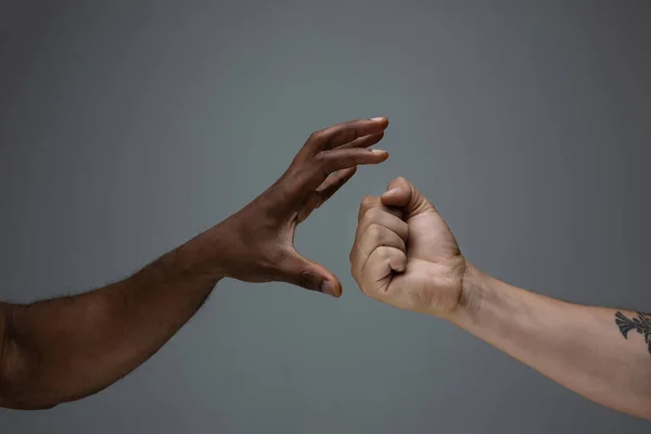 Rasová tolerance. Respektovat společenskou jednotu. Africké a kavkazské ruce gestikulující izolované na šedém pozadí studia — Stock fotografie