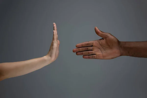 Tolerancia racial. Respetar la unidad social. Africano y caucásico manos gesto aislado en gris estudio fondo — Foto de Stock