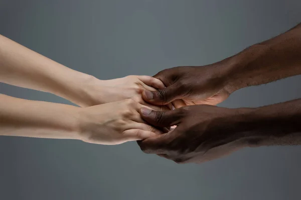 Tolerancia racial. Respetar la unidad social. Africano y caucásico manos gesto aislado en gris estudio fondo —  Fotos de Stock
