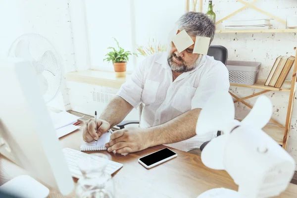 Empresario, gerente en la oficina con computadora y ventilador enfriándose, sintiéndose caliente, enrojecido — Foto de Stock