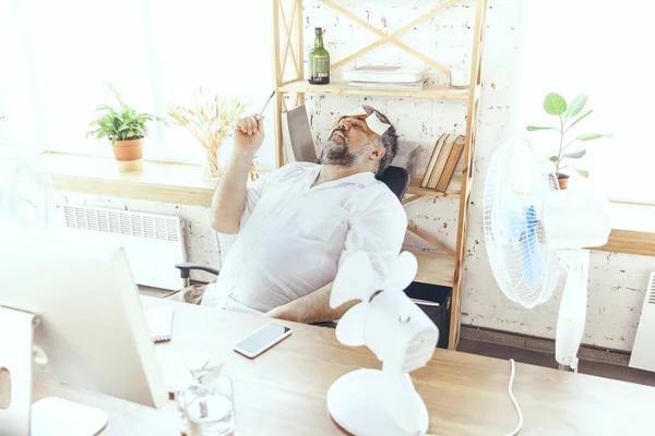 Empresario, gerente en la oficina con computadora y ventilador enfriándose, sintiéndose caliente, enrojecido — Foto de Stock