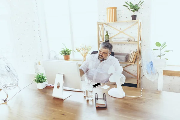 Empresario, gerente en la oficina con computadora y ventilador enfriándose, sintiéndose caliente, enrojecido — Foto de Stock