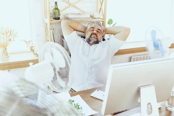 Empresario, gerente en la oficina con computadora y ventilador enfriándose, sintiéndose caliente, enrojecido — Foto de Stock