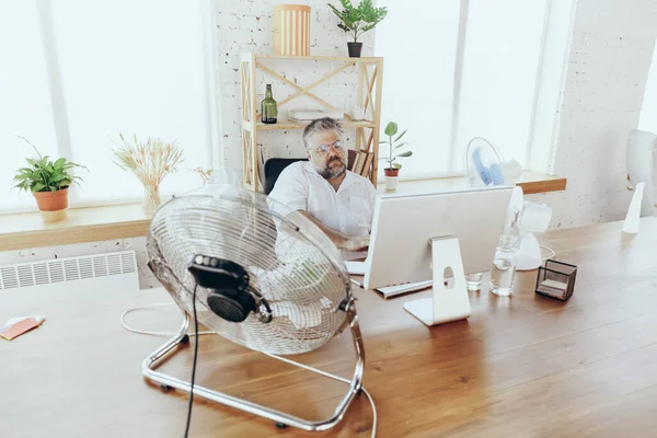 Empresario, gerente en la oficina con computadora y ventilador enfriándose, sintiéndose caliente, enrojecido — Foto de Stock