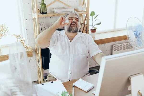 Empresario, gerente en la oficina con computadora y ventilador enfriándose, sintiéndose caliente, enrojecido — Foto de Stock