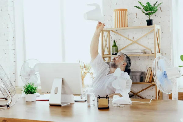 Empresario, gerente en la oficina con computadora y ventilador enfriándose, sintiéndose caliente, enrojecido — Foto de Stock