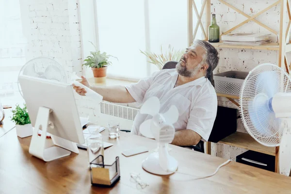 Empresario, gerente en la oficina con computadora y ventilador enfriándose, sintiéndose caliente, enrojecido — Foto de Stock