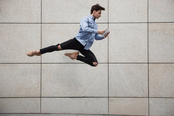 Jumping young buinessman in front of buildings, on the run in jump high — Stock Photo, Image