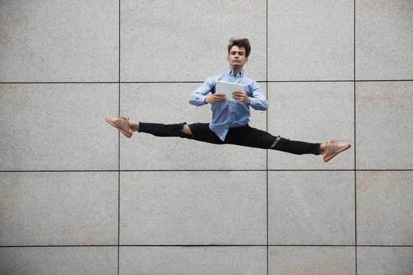 Skákání mladý buinessman před budovami, na útěku ve skoku vysoko — Stock fotografie