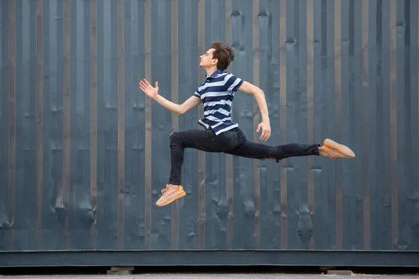 Jumping young buinessman in front of buildings, on the run in jump high — Stock Photo, Image