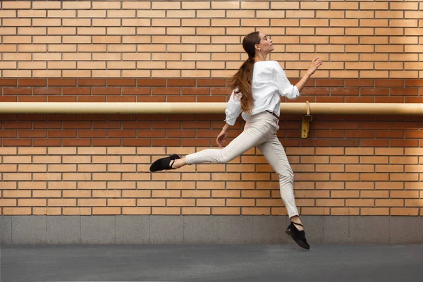 Jeune femme sautante devant les bâtiments, en fuite en saut haut — Photo