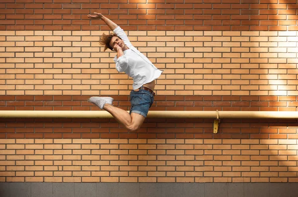 Jumping young man in front of buildings, on the run in jump high — Stock Photo, Image