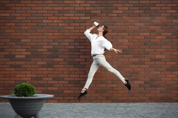 Jumping young woman in front of buildings, on the run in jump high — Stock Photo, Image