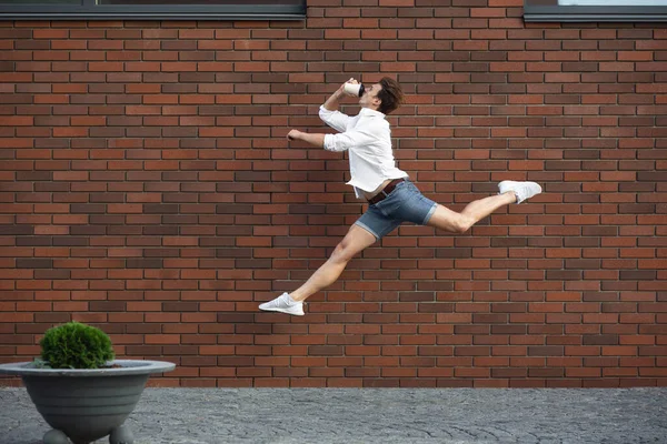 Skoki młody człowiek przed budynkami, w biegu w wysokiej skoku — Zdjęcie stockowe