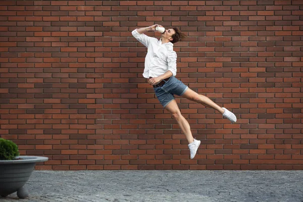 Jumping young man in front of buildings, on the run in jump high — Stock Photo, Image