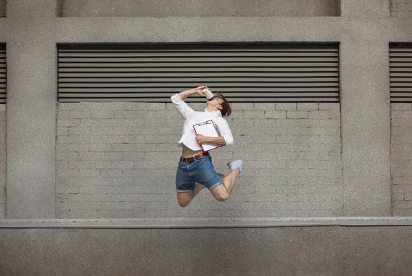 Jumping young man in front of buildings, on the run in jump high — Stock Photo, Image