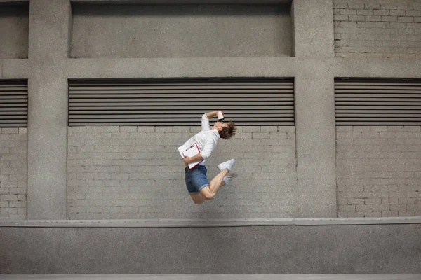 Jumping young man in front of buildings, on the run in jump high — Stock Photo, Image