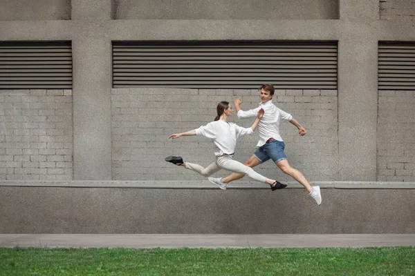 건물 앞에서 뛰고, 높이뛰기를 하고 있는 젊은 부부 — 스톡 사진