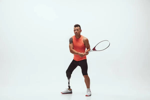 Idrottare med funktionshinder eller amputerad isolerad på vit studio bakgrund. Professionell manlig tennisspelare med benprotesträning och träning i studio. — Stockfoto