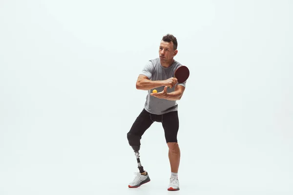 Atleta con discapacidad o amputado aislado en el fondo blanco del estudio. Jugador profesional de tenis de mesa masculino con entrenamiento de prótesis de pierna y práctica en estudio . — Foto de Stock
