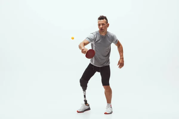 Atleta con discapacidad o amputado aislado en el fondo blanco del estudio. Jugador profesional de tenis de mesa masculino con entrenamiento de prótesis de pierna y práctica en estudio . — Foto de Stock