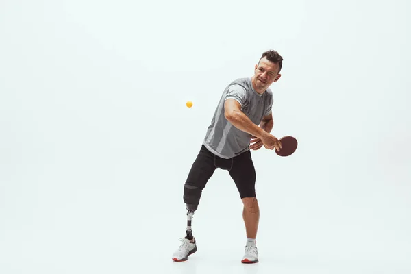 Atleta con discapacidad o amputado aislado en el fondo blanco del estudio. Jugador profesional de tenis de mesa masculino con entrenamiento de prótesis de pierna y práctica en estudio . — Foto de Stock