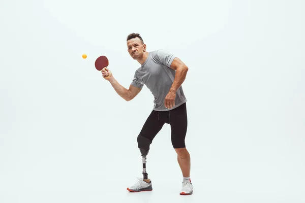 Atleta con discapacidad o amputado aislado en el fondo blanco del estudio. Jugador profesional de tenis de mesa masculino con entrenamiento de prótesis de pierna y práctica en estudio . — Foto de Stock