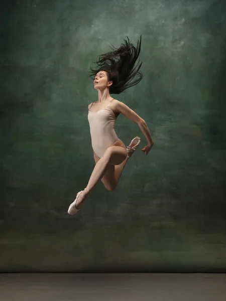Young graceful tender ballerina on dark green studio background — Stock Photo, Image