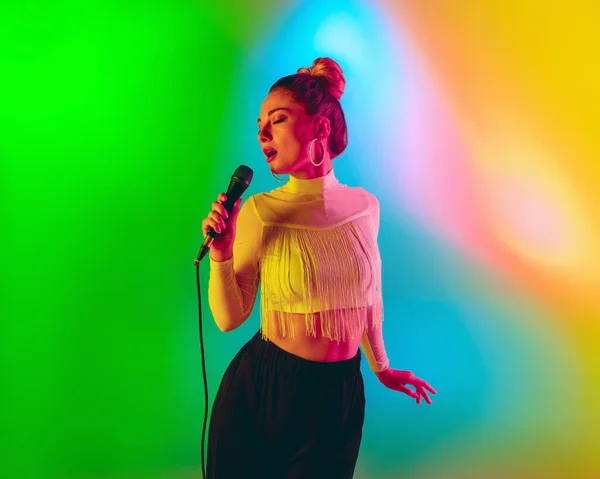 Jonge Kaukasische muzikant speelt, zingt op gradiënt achtergrond in neon licht. Concept van muziek, hobby, festival — Stockfoto