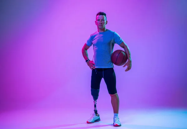 Athlète handicapé ou amputé isolé sur fond de studio dégradé. Joueur professionnel de basket-ball masculin avec entraînement par prothèse de jambe et pratique en studio. — Photo