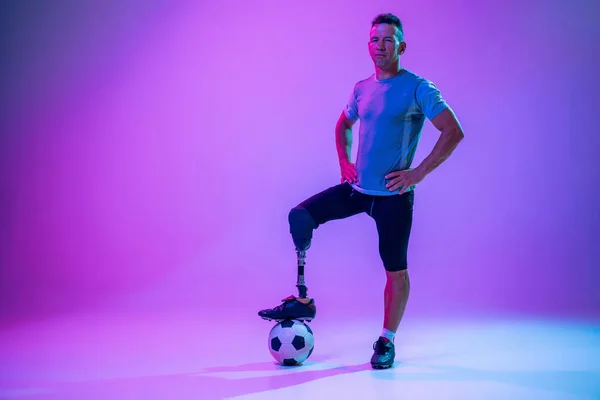 Athlète handicapé ou amputé isolé sur fond de studio dégradé. Joueur professionnel de football masculin avec entraînement par prothèse de jambe et pratique en studio. — Photo