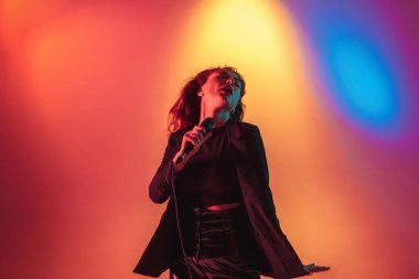Genç beyaz müzisyen, kadın şarkıcı, arka planda neon ışıkta şarkı söylüyor. Müzik anlayışı, hobi, festival