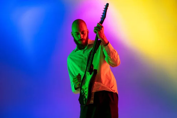 Jonge Kaukasische muzikant, gitarist op een gradiënt achtergrond in neon licht. Concept van muziek, hobby, festival — Stockfoto