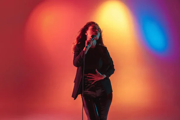 Jovem músico caucasiano, cantora feminina se apresentando em fundo gradiente em luz de néon. Conceito de música, hobby, festival — Fotografia de Stock