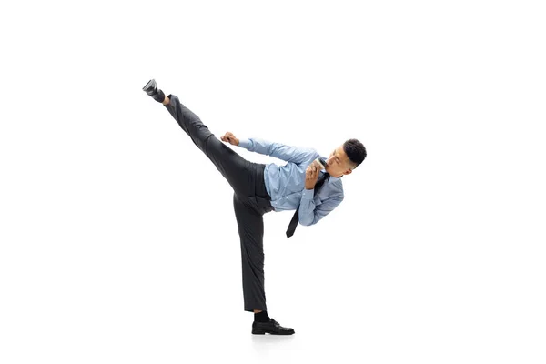 Man in office clothes practicing taekwondo on white background. Unusual look for businessman in motion, action. Sport, healthy lifestyle. Stock Image