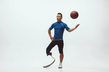 Engelli ya da sakatlığı olan bir sporcu beyaz stüdyo arka planında izole edilmiş. Stüdyoda bacak protezi eğitimi almış profesyonel erkek basketbolcu..