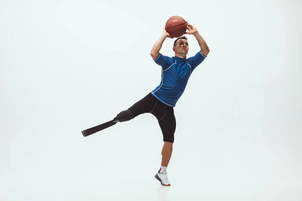 장애가 있거나 다리가 절단 된 선수는 화이트 스튜디오 배경에서 격리되어 있다. 의족 훈련을 받고 스튜디오에서 연습하는 직업적 인 남자 농구 선수. — 스톡 사진