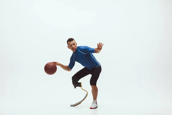 Atleet met een handicap of geamputeerde geïsoleerd op witte studio achtergrond. Professionele mannelijke basketbalspeler met been prothese training en oefenen in de studio. — Stockfoto