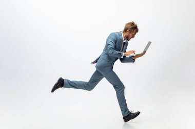 Ofis elbiseli bir adam koşuyor, beyaz arka planda koşuyor. Hareket halindeki bir iş adamı için alışılmadık bir görünüm. Spor, sağlıklı yaşam tarzı.