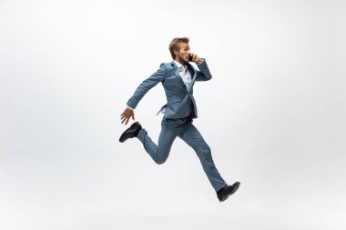 Ofis elbiseli bir adam koşuyor, beyaz arka planda koşuyor. Hareket halindeki bir iş adamı için alışılmadık bir görünüm. Spor, sağlıklı yaşam tarzı.