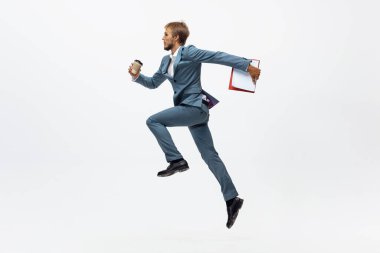 Ofis elbiseli bir adam koşuyor, beyaz arka planda koşuyor. Hareket halindeki bir iş adamı için alışılmadık bir görünüm. Spor, sağlıklı yaşam tarzı.