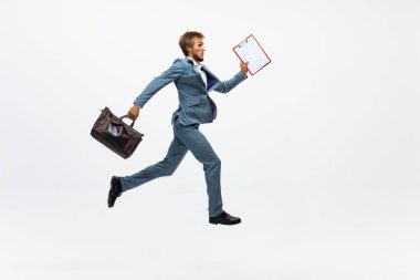 Ofis elbiseli bir adam koşuyor, beyaz arka planda koşuyor. Hareket halindeki bir iş adamı için alışılmadık bir görünüm. Spor, sağlıklı yaşam tarzı.