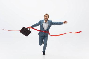 Ofis elbiseli bir adam koşuyor, beyaz arka planda koşuyor. Hareket halindeki bir iş adamı için alışılmadık bir görünüm. Spor, sağlıklı yaşam tarzı.