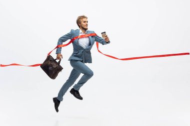 Ofis elbiseli bir adam koşuyor, beyaz arka planda koşuyor. Hareket halindeki bir iş adamı için alışılmadık bir görünüm. Spor, sağlıklı yaşam tarzı.