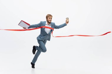 Ofis elbiseli bir adam koşuyor, beyaz arka planda koşuyor. Hareket halindeki bir iş adamı için alışılmadık bir görünüm. Spor, sağlıklı yaşam tarzı.